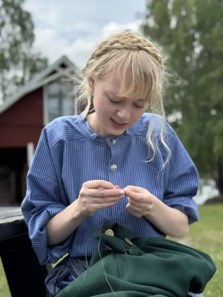 Jente i blå busserull som syr