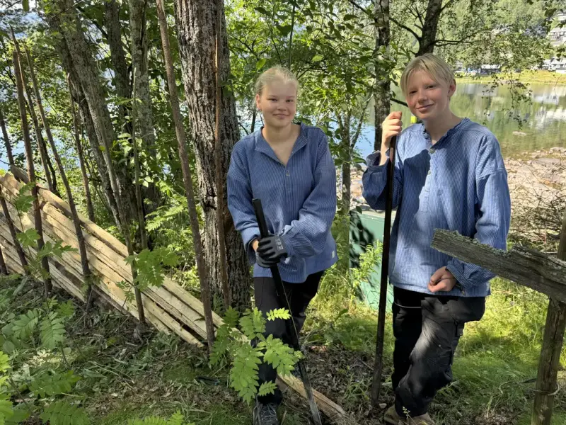 Ei jente og ein gut i blå busserull som byggjar skigard