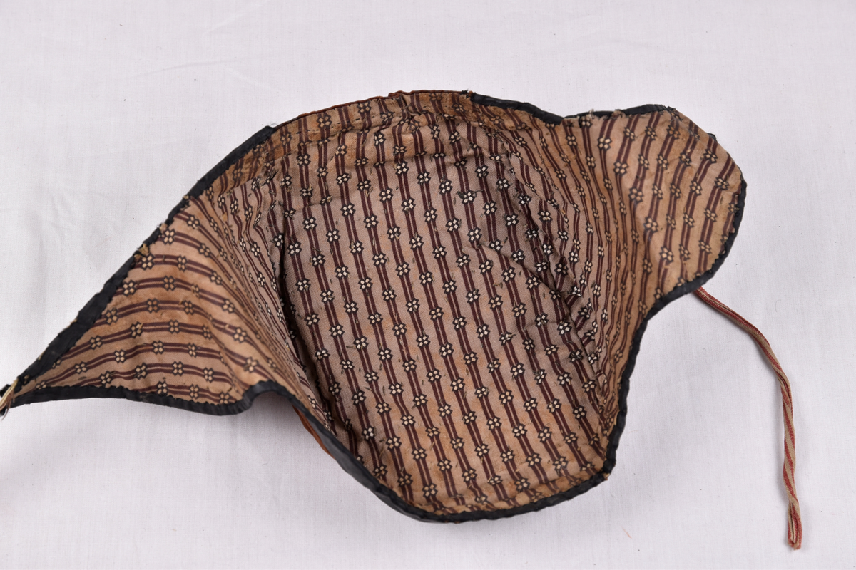 Damelue med gyllenbrunt silkstoff og svart kant. Foret er stripete.