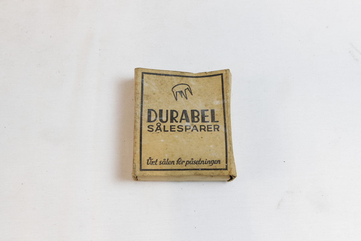 Rektangulær eske som inneholder sirkulære sålesparer med tre pigger.
