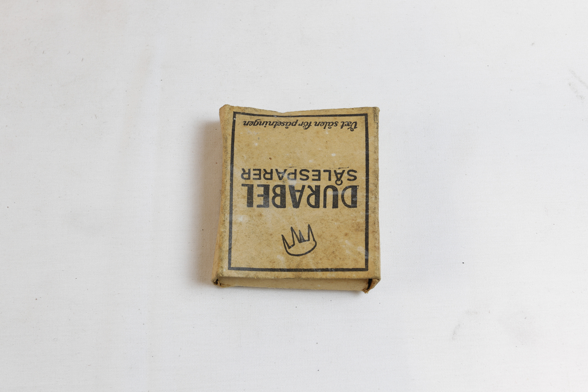 Rektangulær eske som inneholder sirkulære sålesparer med tre pigger.
