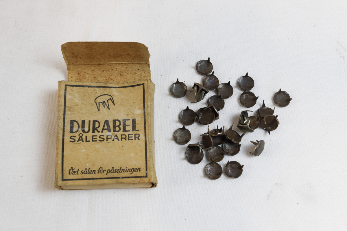 Rektangulær eske som inneholder sirkulære sålesparer med tre pigger.
