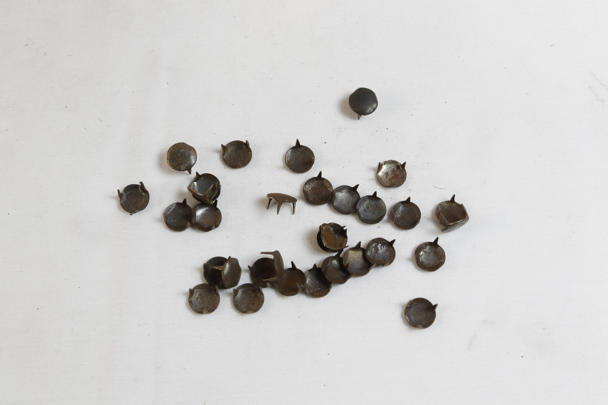 Rektangulær eske som inneholder sirkulære sålesparer med tre pigger.
