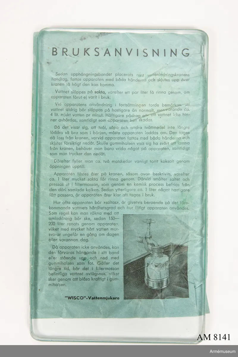 Vattenmjukare Wisco. Tillverkad av grön och svart plåt och gummi. Klistrad etikett  "Wisco vattenmjukare Patent". I botten med vit oljefärg "C". Apparaten skall sättas på en vattenkran. Vattnet får rinna igenom med högst 4 min/liter (sic!) tryck. Rening av apparaten görs med 2 matskedar salt som läggs i gummivalsen varefter en liter vatten sakta får rinna igenom. Bruksanvisning finns i  förpackningen. Ingår i fotomaterielsats 7 låda 2.