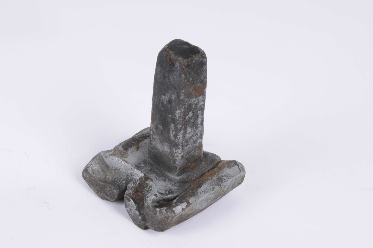 Falsmejsel, med kort hals och stor bred botten, med två skåror. Den ser ut att ha smält ihop något. Målad med grå färg, sotig och rostig. 