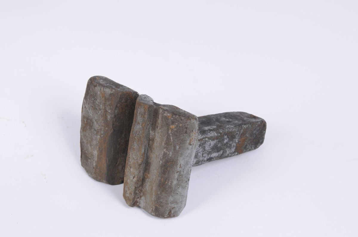 Falsmejsel, med kort hals och stor bred botten, med två skåror. Den ser ut att ha smält ihop något. Målad med grå färg, sotig och rostig. 