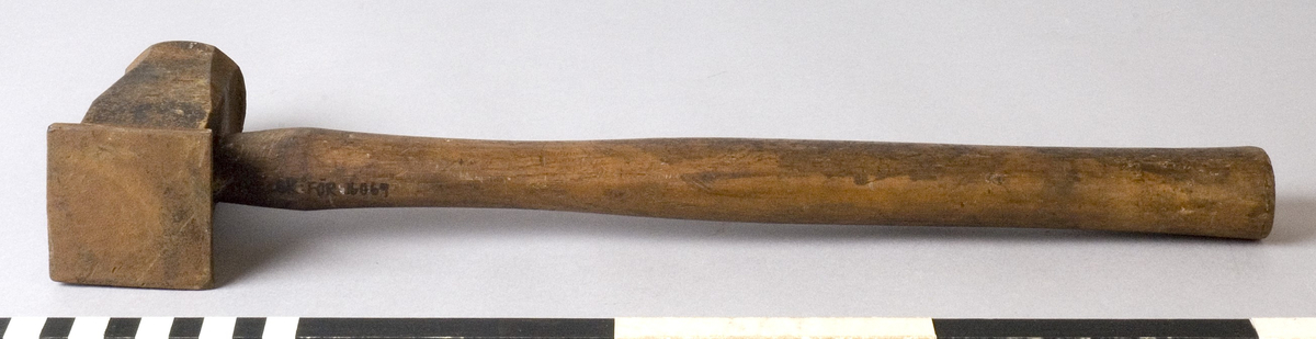 Hammare med skaft av trä. Fyra rostiga skruvhuvuden drivna ner i skaftet. Rostigt huvud.
Märkt: S IMPORT.