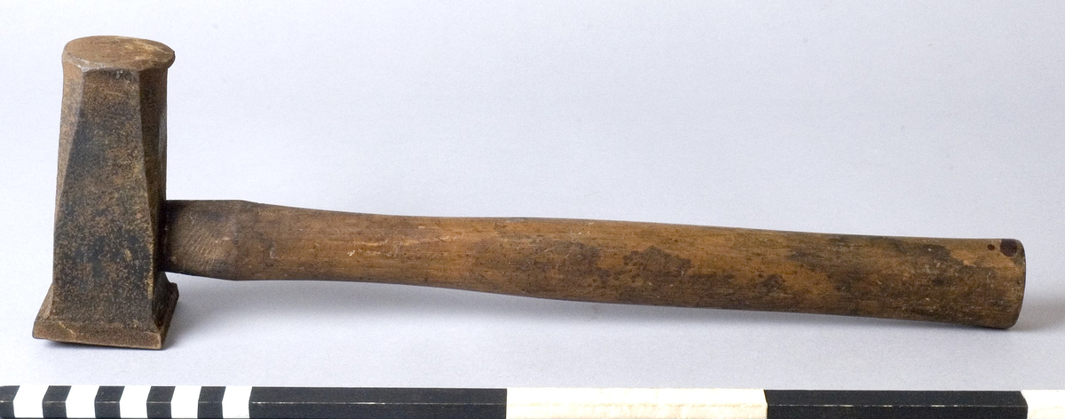 Hammare med skaft av trä. Fyra rostiga skruvhuvuden drivna ner i skaftet. Rostigt huvud.
Märkt: S IMPORT.