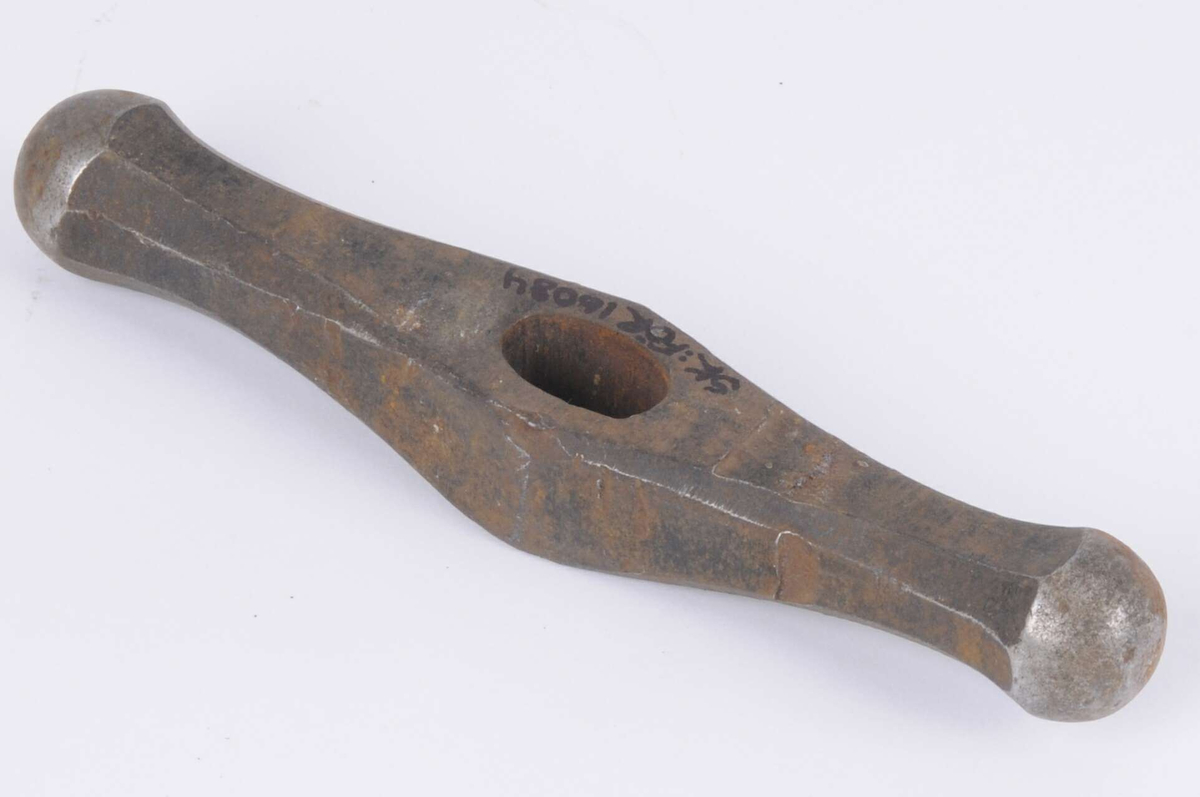 Hammare utan skaft. Rostig, med hackmärken. Lätt böjd i formen, två runda kupiga slagytor.