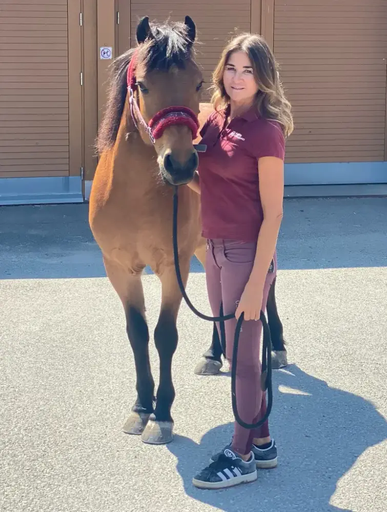 En dame leier en brun ponni med rød grime. 