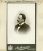 Porträtt av länsmaskinist John Carlsson i Linköping. Hans yrkestitel kan behöva förklaras och finner sitt behov i industrialismens alltmer ökade mekanisering inom jordbruket. Hushållningssällskapet i Östergötland hade inrättat tjänsten redan 1875 men indragit den under 1880-talet på grund av ekonomiska skäl. Behovet av stöd till jordbrukare vid uppsättningar och reparationer av jordbruksmaskiner kvarstod dock och år 1888 återinfördes tjänsten ånyo och från 1891 innehades den av den avbildade John  Carlsson. År 1905 utgav han 