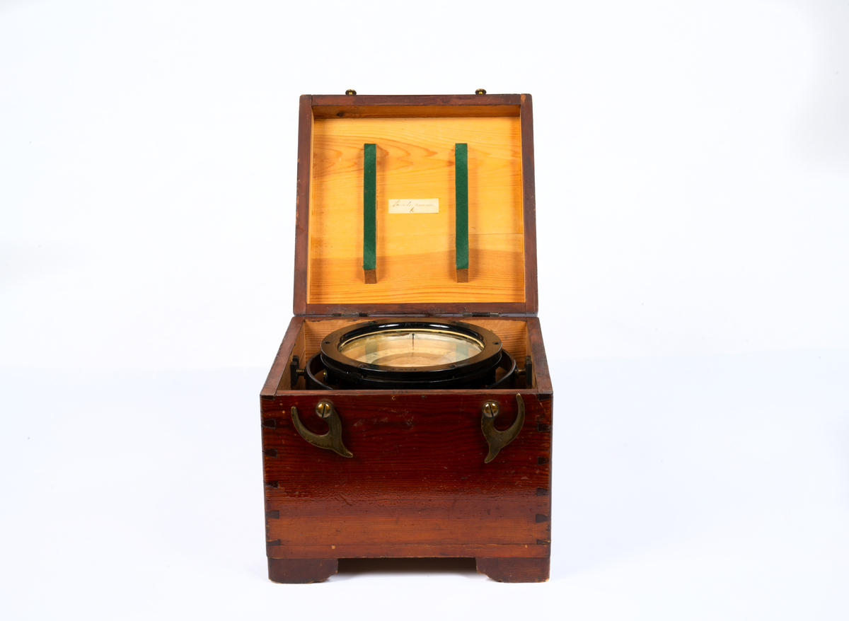 Trälåda låda till spritkompass med kardansk upphängning (del 1) . Med nakterhus (2). Lådan är av björk och har skjutlock. Fernissad. Innehåller sex stycken kompensationsmagneter.