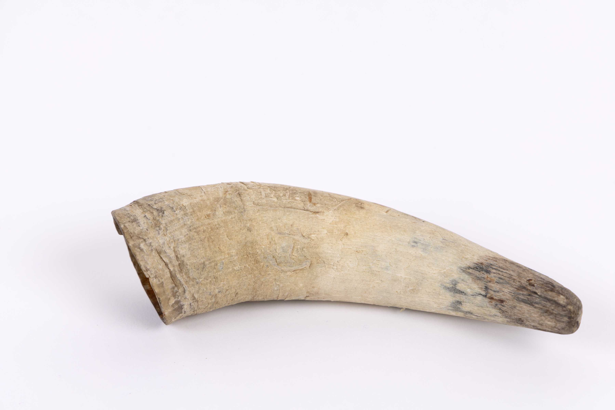 Fetthorn funnet ved Kongshavn ved Alvøen i Bergen. Kremmerhusformet fetthorn av bein med rett kant øverst. Initialer og skipsnavn innrisset sammen med ett anker. Del av en last med flere fetthorn sammen med restene av ett skog.