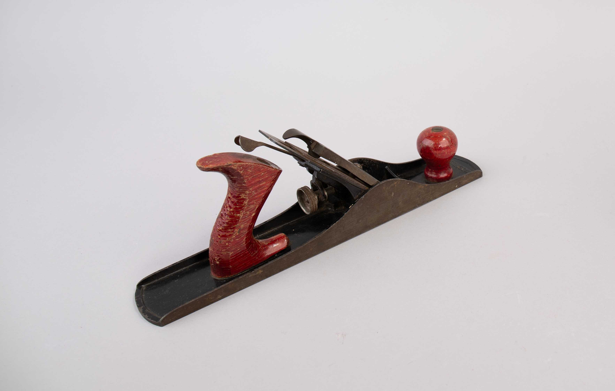 Pusshøvel. Høvel av metall med håndtak i rødmalt tre. Del av innhold i verktøykoffert.