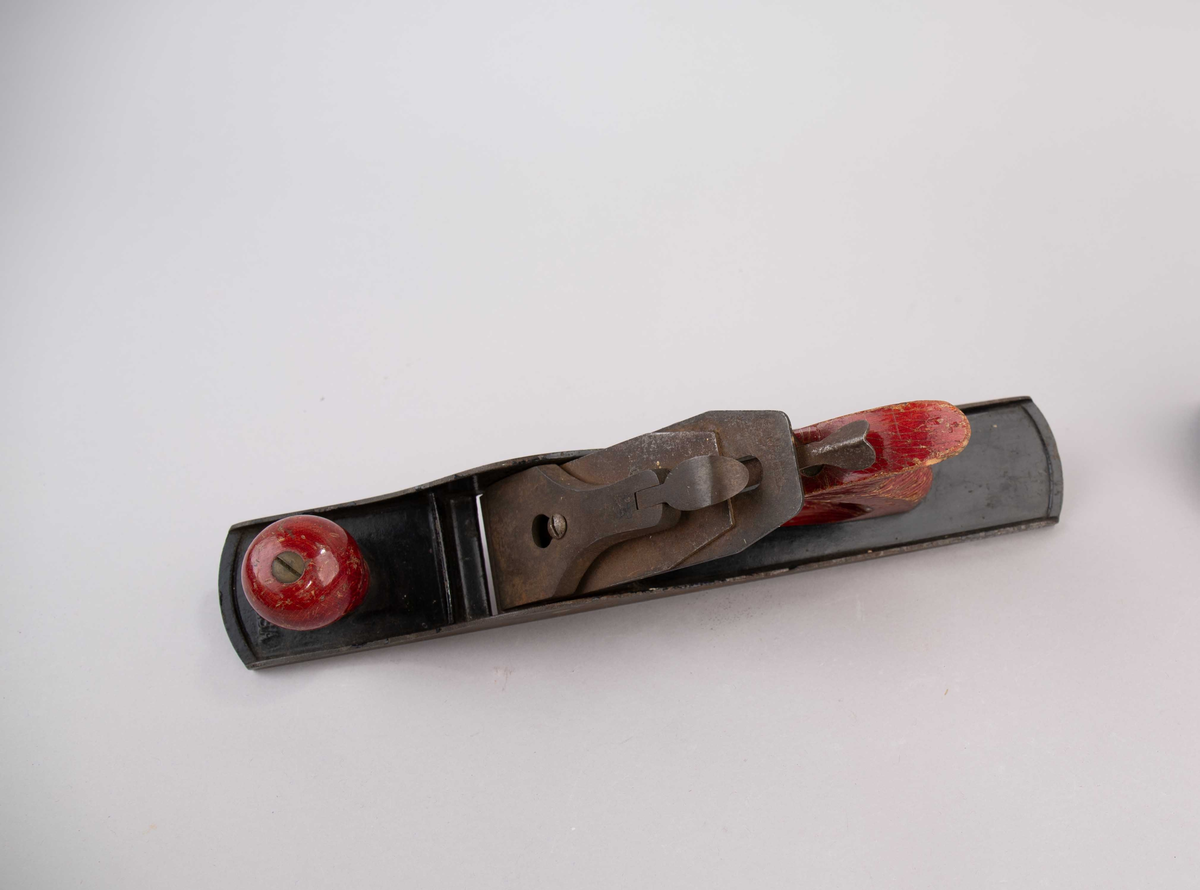 Pusshøvel. Høvel av metall med håndtak i rødmalt tre. Del av innhold i verktøykoffert.