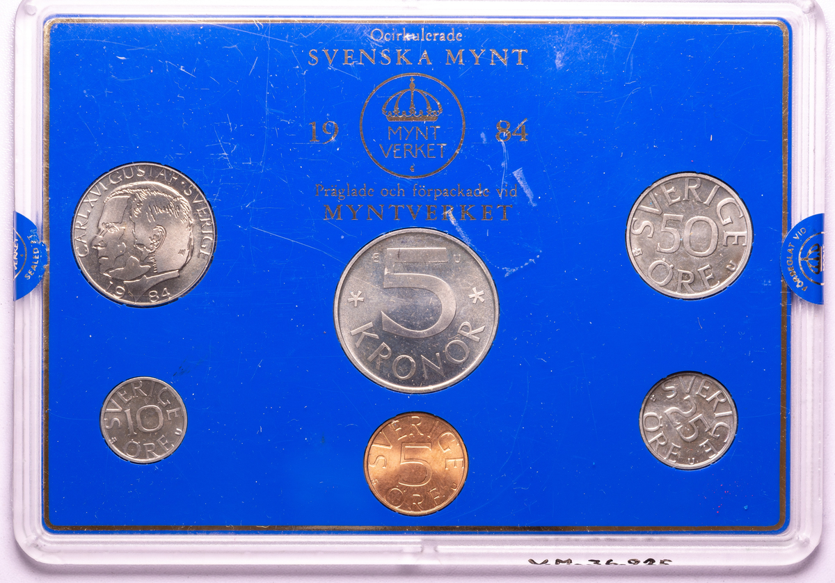 I ett plastset finns 1984 års svenska mynt samlade. Vart mynt på sin plats på en blå botten. Måttet avser plastfodralet. 