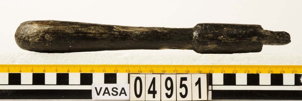 Svarvat skaft till mindre klubba. Ansatsen har ett kvadratiskt tvärsnitt. Ett hörn av ansatsen är avslagen i övrigt är skaftet helt intakt. Under ansatsen finns ett cylindriskt parti, vilket avslutas med en dekorrand. Därefter är skaftet koniskt och vidgar sig nedtill, för att i änden avslutas i en rundning. Vid ansatsen finns rester av grön korrosion.

För mer information se Dokumentationsblankett under Referenser – Länkade filer.