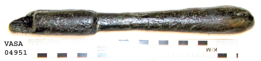 Svarvat skaft till mindre klubba. Ansatsen har ett kvadratiskt tvärsnitt. Ett hörn av ansatsen är avslagen i övrigt är skaftet helt intakt. Under ansatsen finns ett cylindriskt parti, vilket avslutas med en dekorrand. Därefter är skaftet koniskt och vidgar sig nedtill, för att i änden avslutas i en rundning. Vid ansatsen finns rester av grön korrosion.

För mer information se Dokumentationsblankett under Referenser – Länkade filer.