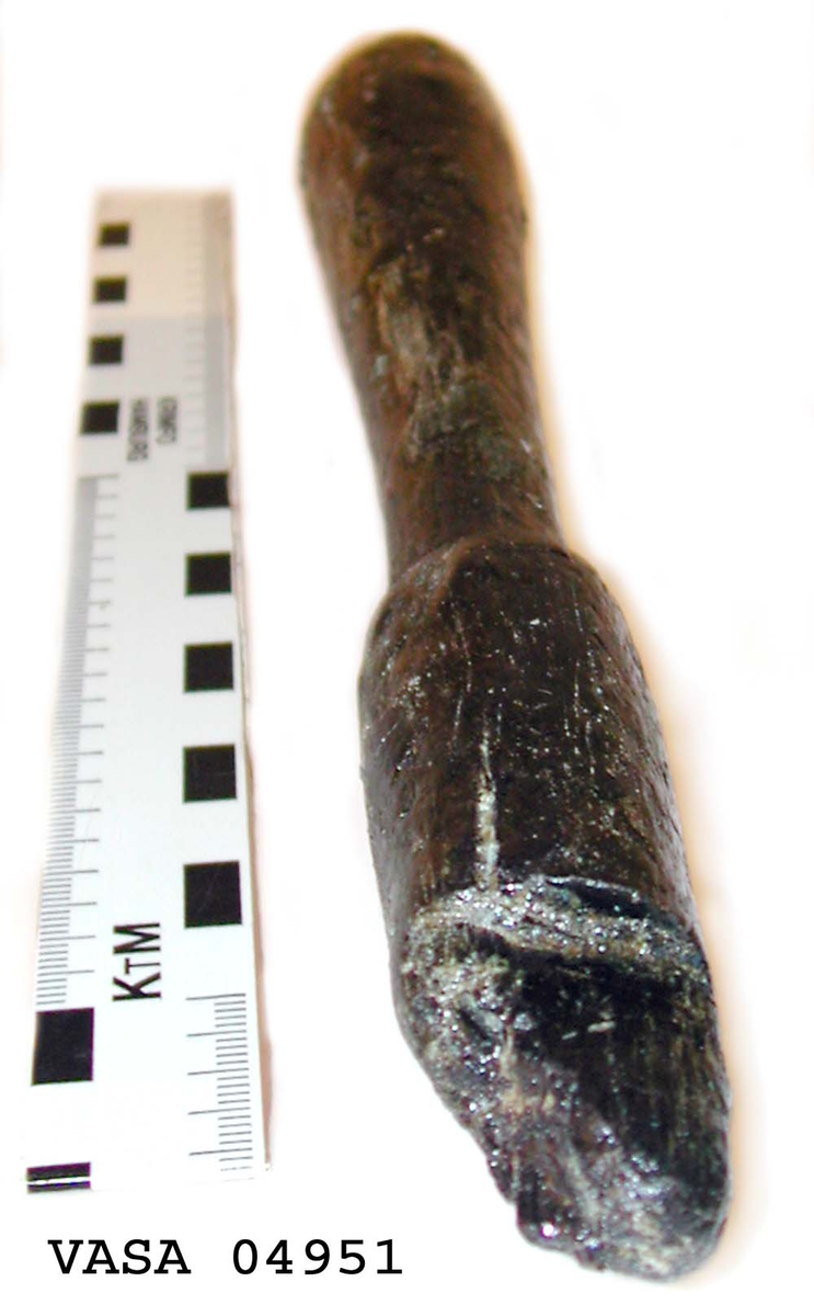 Svarvat skaft till mindre klubba. Ansatsen har ett kvadratiskt tvärsnitt. Ett hörn av ansatsen är avslagen i övrigt är skaftet helt intakt. Under ansatsen finns ett cylindriskt parti, vilket avslutas med en dekorrand. Därefter är skaftet koniskt och vidgar sig nedtill, för att i änden avslutas i en rundning. Vid ansatsen finns rester av grön korrosion.

För mer information se Dokumentationsblankett under Referenser – Länkade filer.