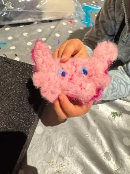 Et barn viser frem det kan har tovet, en liten rosa figur med øyne