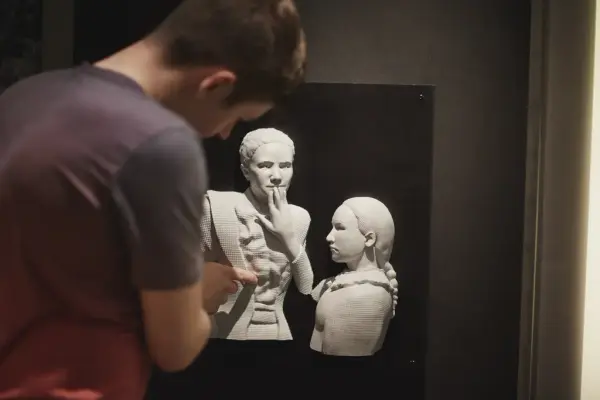 Et bilde fra Norsk døvemuseum som viser en person som studerer en taktil modell av to personer