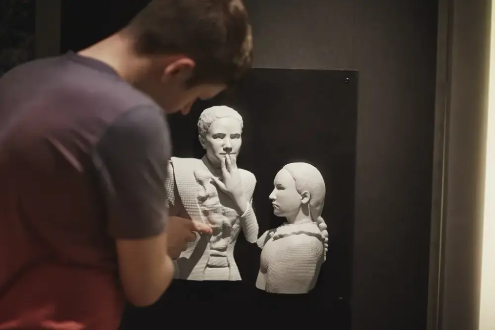 Et bilde fra Norsk døvemuseum som viser en person som studerer en taktil modell av to personer