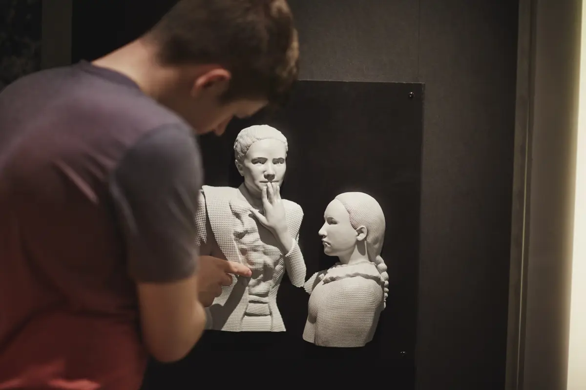 Et bilde fra Norsk døvemuseum som viser en person som studerer en taktil modell av to personer