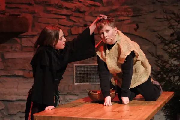 Lussi i helt svaret klær løfter en gutt kledd i striesekk opp etter håret.