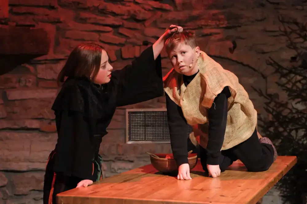 Lussi i helt svaret klær løfter en gutt kledd i striesekk opp etter håret.