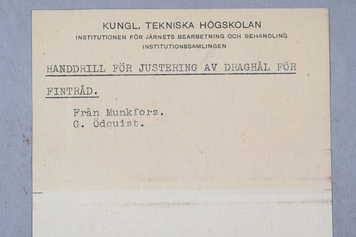 Prov på handdrill för justering av draghål för fintråd. Tillverkad i Munkfors. Signerad G. Ödquist. Tillhörande lapp med samma notering.