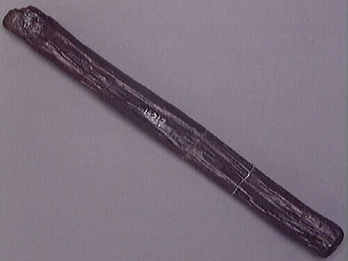 Ett skaft till en hammare. Skaftet är långsmalt och har ett rektangulärt tvärsnitt. Skaftet är avfasat i den ände där hammarhuvudet suttit fästat. Genom skaftets nedre del, som är något förtjockad samt rundad, är ett hål borrat.

Skaftet är slitet. På skaftets mitt syns spår efter en lagning, troligtvis utförd i samband med konserveringen av skaftet.

För mer information se Dokumentationsblankett under Referenser – Länkade filer.

Text in English: The handle or helve of a hammer. The shaft is long and rectangular shaped in cross-section. The end that fits into the hammer head is bevelled, while the other end is somewhat thicker and rounded, with a hole bored through.

The helve is worn and appears to have been repaired at the middle, probably done in connection with its conservation.

For more information see the Documentation form under References – Linked files.