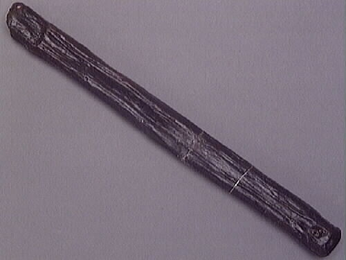 Ett skaft till en hammare. Skaftet är långsmalt och har ett rektangulärt tvärsnitt. Skaftet är avfasat i den ände där hammarhuvudet suttit fästat. Genom skaftets nedre del, som är något förtjockad samt rundad, är ett hål borrat.

Skaftet är slitet. På skaftets mitt syns spår efter en lagning, troligtvis utförd i samband med konserveringen av skaftet.

För mer information se Dokumentationsblankett under Referenser – Länkade filer.

Text in English: The handle or helve of a hammer. The shaft is long and rectangular shaped in cross-section. The end that fits into the hammer head is bevelled, while the other end is somewhat thicker and rounded, with a hole bored through.

The helve is worn and appears to have been repaired at the middle, probably done in connection with its conservation.

For more information see the Documentation form under References – Linked files.