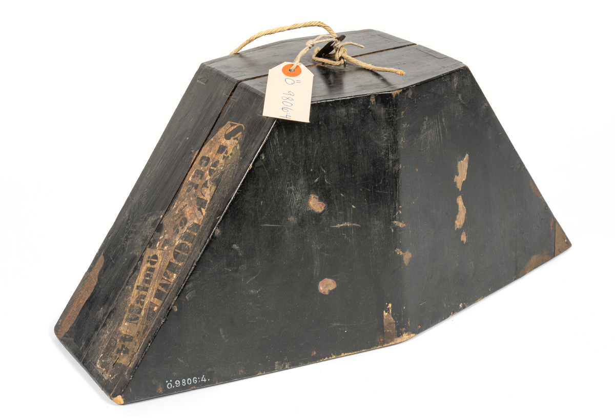 Paradhatt med fodral av trä. Hatten trekantig. Av snart silkesfelb med svarta kantband. Gul kokard med guldgalon och ankarknapp. Buljoner i ändarna. Rödd foder av siden. Firmastämpel (otydlig). Käkrem.