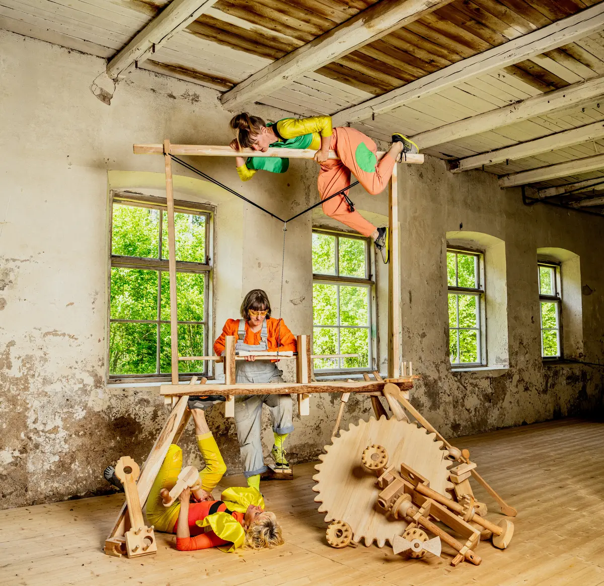 Tre kvinnor vid en träställning med fyra fönster i bakgrunden.