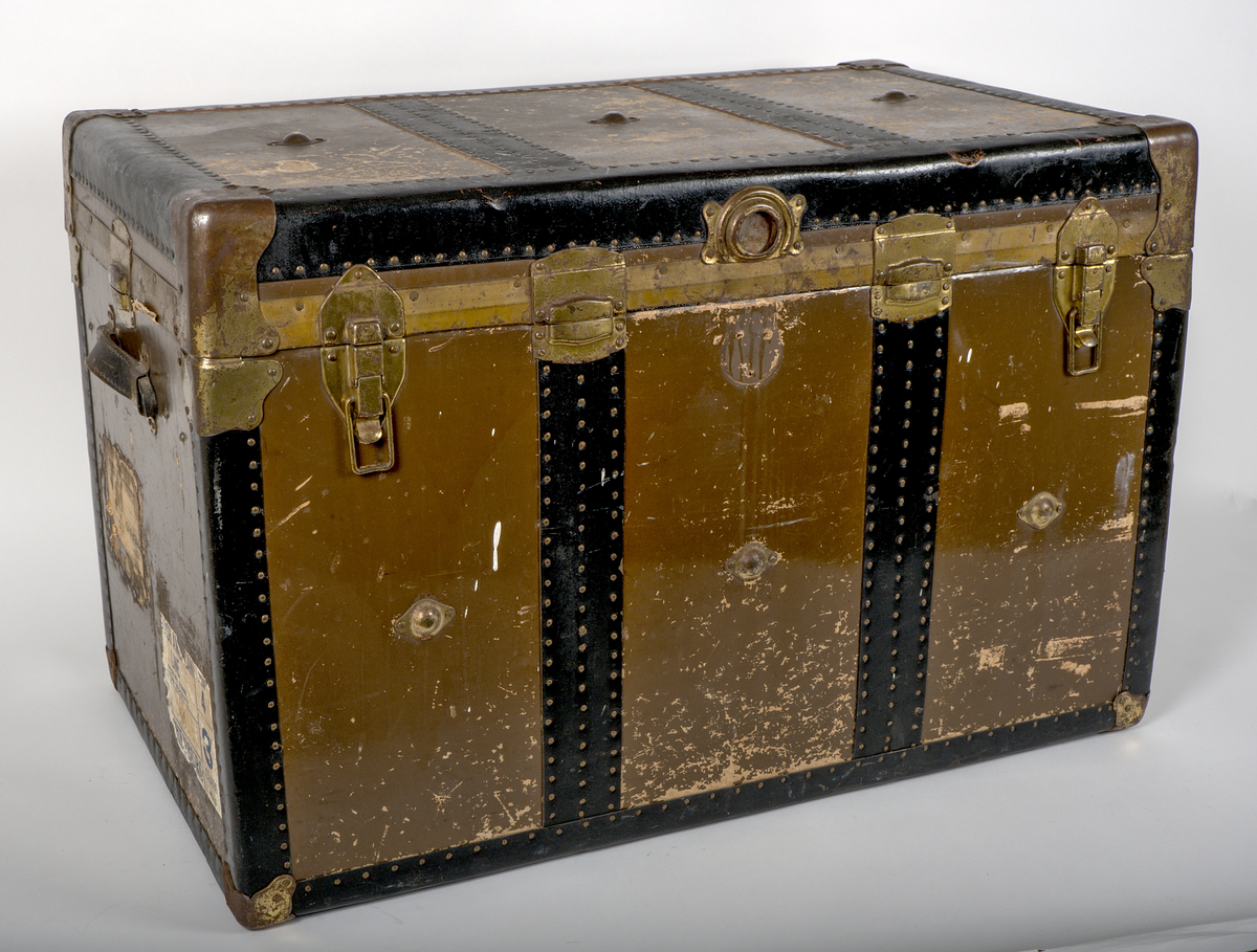 a) Rektangulär resekoffert med trästomme, utvändigt klädd i brunt papp och förstärkt med svartmålat konstläder. Kofferten är försedd med beslag och stötskydd av mässingspläterat stål. På vardera kortsida finns ett bärhandtag av kraftigt brunt läder. Koffertens framsida är försedd med låsanordningar bestående av två haspar samt i mitten ett ofullständigt lås, där låsdelen på kistans underdel saknas.

Invändigt har kofferten en uttagbar låda av papp, vilande på ribbor i kistans övre del. Insidan är klädd med grönt papper i geometriskt mönster. Bottendelen av lådan skyddas av ett smörpapper med blå prickar på vit botten. I kistans botten finns ett skyddande smörpapper med geometriska mönster i vitt, grönt och rött.

På vänster kortsida finns två stycken etiketter:

1. Swedish America Line.
2. Railway Express Agency (Attleboro, Massachusetts). Under denna etikett sitter fragment av en etikett i samma stil.

Se fotografi.

b) Pappersetikett med öljett, fäst i ståltråd: "Svenska.. Amerika. N: 936. Göteborgs Andra Bärarelag".