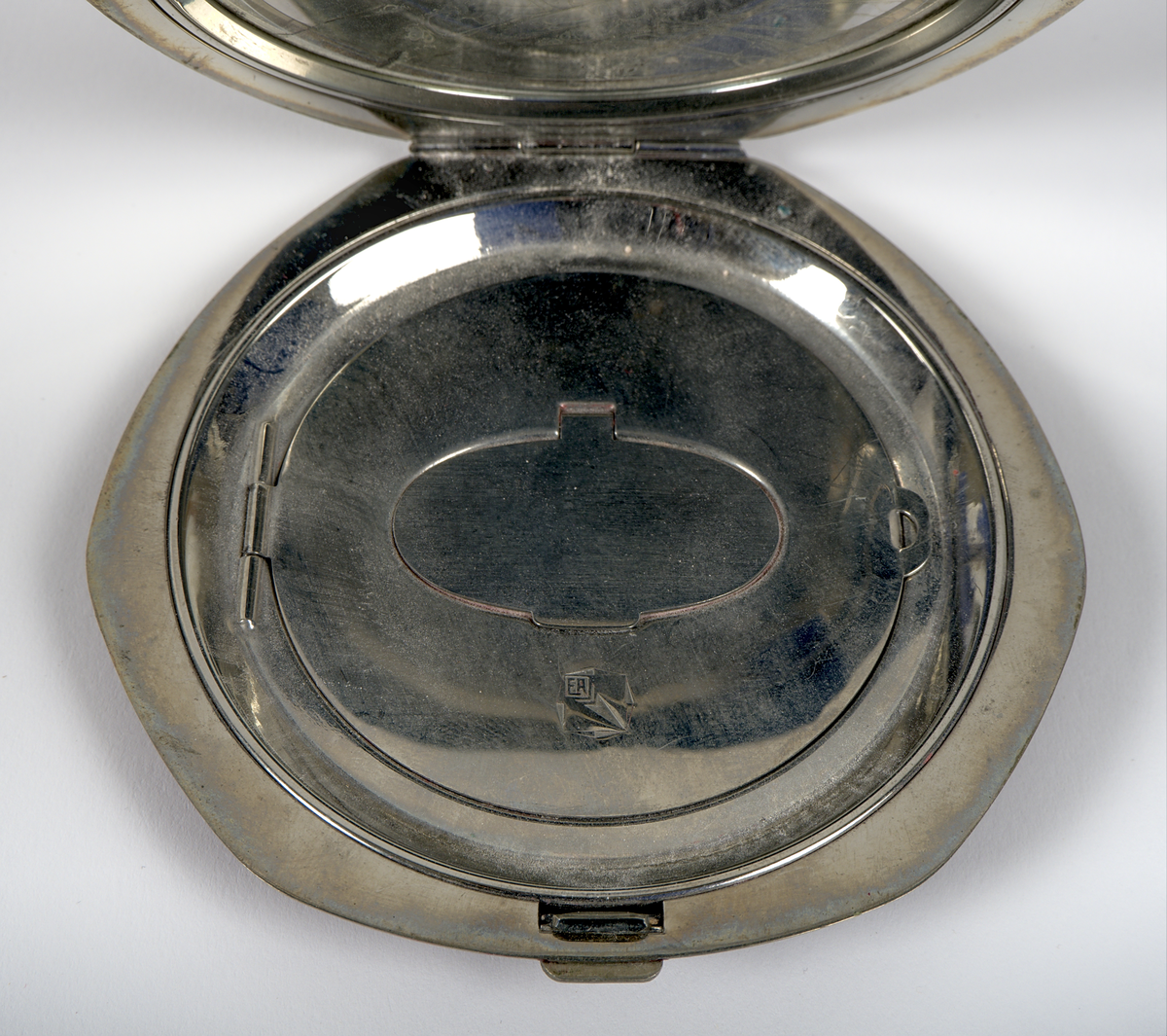 Oval puderdosa i metall med vinröd emaljerad yta. På ovansidan finns en metallplatta med silverfärgad text mot blå bakgrund: "1933, A Century of Progress, Chicago".

På insidan av locket sitter en spegel, medan botten har en rosa tyginsats för puder, märkt "ELGIN VANITY". Dosan stängs med en låsmekanism kopplad till en knapp.