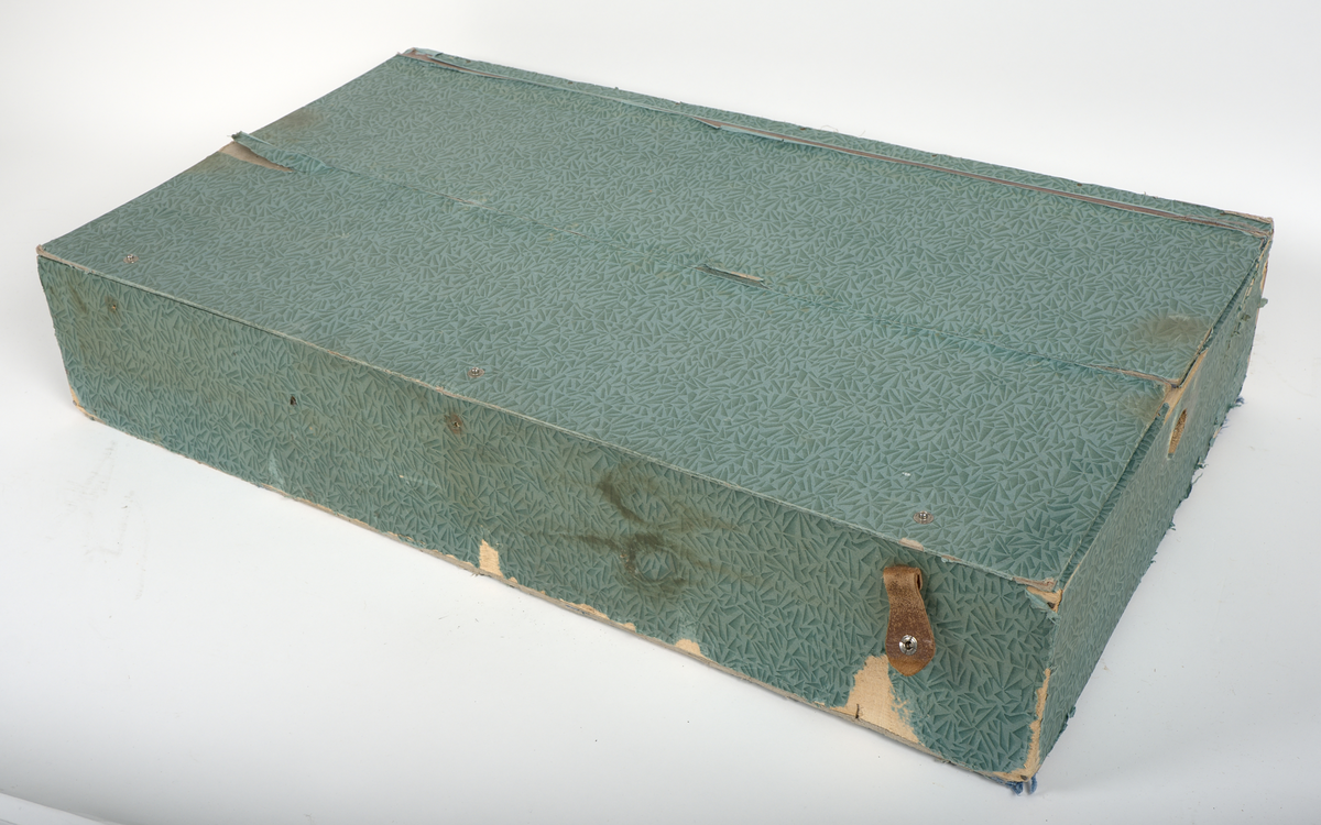 a) Rektangulär resekoffert med trästomme, utvändigt klädd i brunt papp och förstärkt med svartmålat konstläder. Kofferten är försedd med beslag och stötskydd av mässingspläterat stål. På vardera kortsida finns ett bärhandtag av kraftigt brunt läder. Koffertens framsida är försedd med låsanordningar bestående av två haspar samt i mitten ett ofullständigt lås, där låsdelen på kistans underdel saknas.

Invändigt har kofferten en uttagbar låda av papp, vilande på ribbor i kistans övre del. Insidan är klädd med grönt papper i geometriskt mönster. Bottendelen av lådan skyddas av ett smörpapper med blå prickar på vit botten. I kistans botten finns ett skyddande smörpapper med geometriska mönster i vitt, grönt och rött.

På vänster kortsida finns två stycken etiketter:

1. Swedish America Line.
2. Railway Express Agency (Attleboro, Massachusetts). Under denna etikett sitter fragment av en etikett i samma stil.

Se fotografi.

b) Pappersetikett med öljett, fäst i ståltråd: "Svenska.. Amerika. N: 936. Göteborgs Andra Bärarelag".