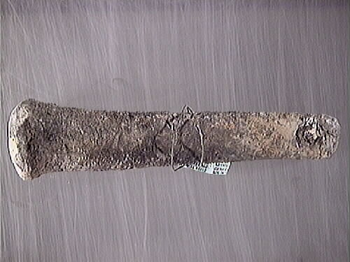 Lod av bly. Fyrkantig profil med avtrubbade ändar. Genomgående hål en den smalare änden har fungerat som ögla. Hålet är fyllt med avlagringar och eventuellt represter. Gråmatt, porös yta.

För mer information se Dokumentationsblankett under Referenser – Länkade filer.