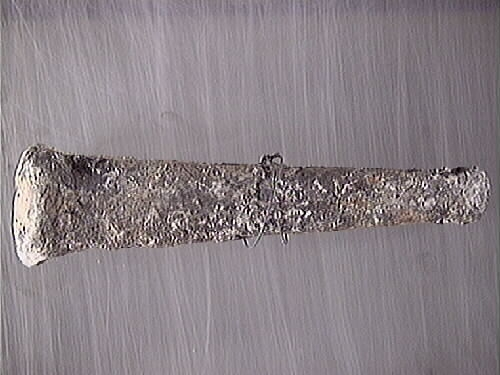 Lod av bly. Fyrkantig profil med avtrubbade ändar. Genomgående hål en den smalare änden har fungerat som ögla. Hålet är fyllt med avlagringar och eventuellt represter. Gråmatt, porös yta.

För mer information se Dokumentationsblankett under Referenser – Länkade filer.