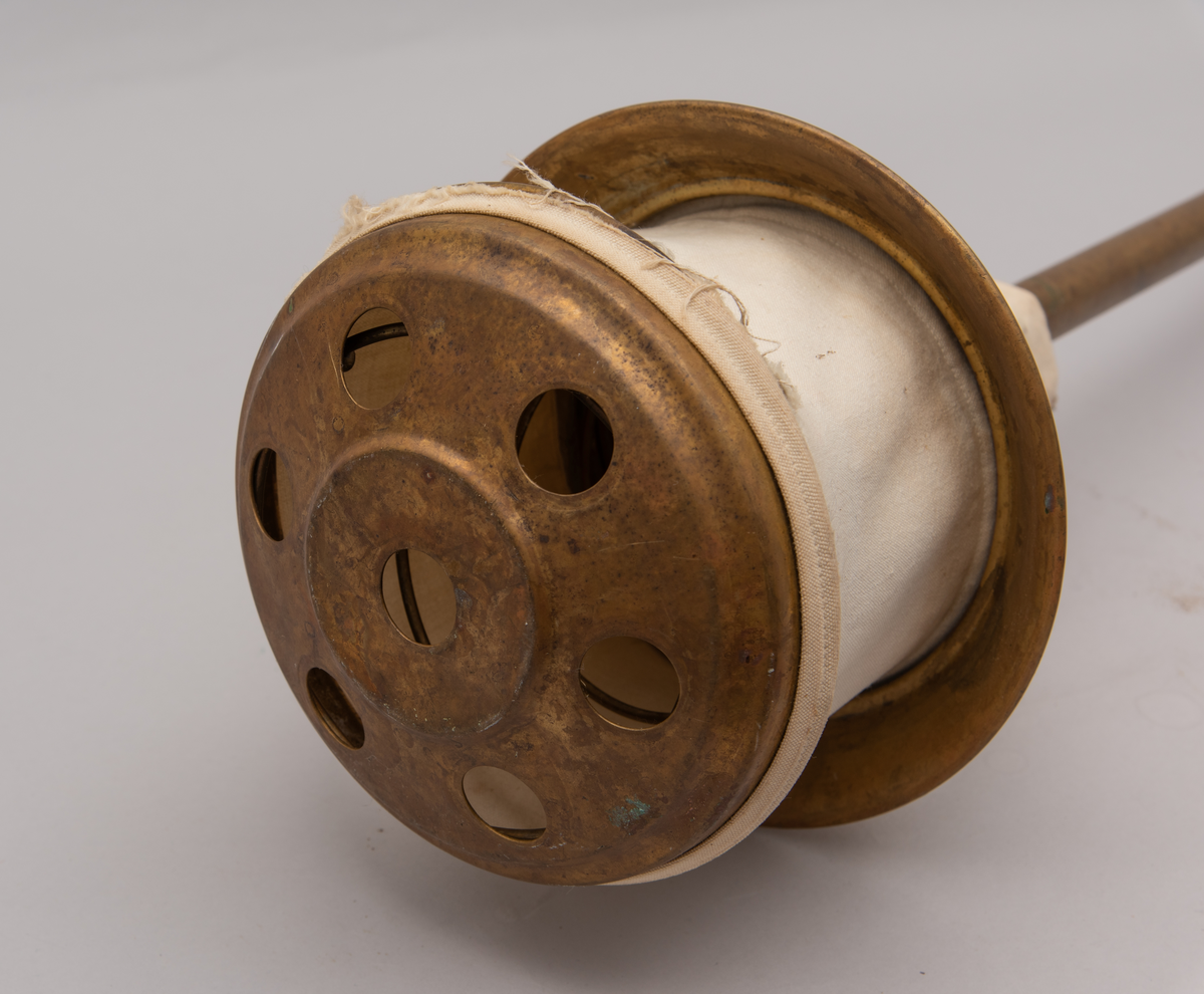 Vaskeredskap bestående av et messingrør til håndtak og et pumpehode i enden. Pumpehodet består av to messinglokk forbundet med et sluttet tekstilbånd, og en metallfjær inni som gir motstand. Nederste lokk har hull for å slippe inn vaskevannet. Godset er stemplet med Rena og initialene O.J.