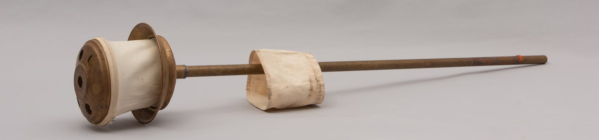 Vaskeredskap bestående av et messingrør til håndtak og et pumpehode i enden. Pumpehodet består av to messinglokk forbundet med et sluttet tekstilbånd, og en metallfjær inni som gir motstand. Nederste lokk har hull for å slippe inn vaskevannet. Godset er stemplet med Rena og initialene O.J.