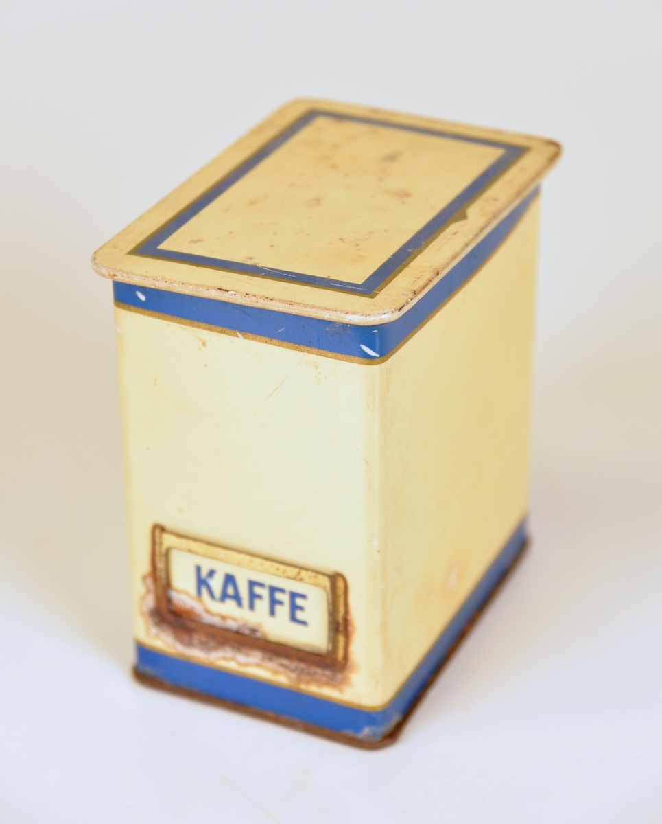 Gula ålåtburkar med blå dekor. Etiketthållare , två med KAFFE tryckt på burken, en med vit plastetikett med text "SOCKER" i svart och en med etikett med "KAKAO".  Det kan vara så att när man köpt kaffe har man fått det i burken samt lösa etiketter för att återanvända burken till annat när kaffet var slut.

Från Arne Ekströms handelsmuseum.