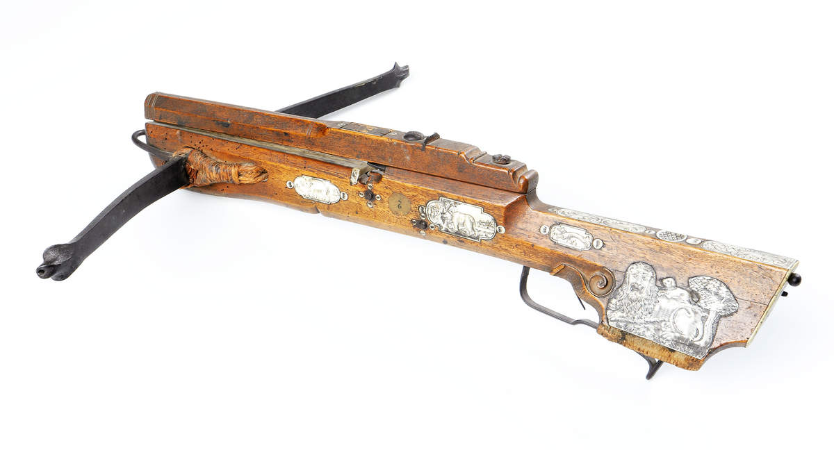 Armborst tillverkat i valnötsträ med båge av stål, försedd med inbygt lås med snälltryck. Stocken har inläggningar av elfenben i medaljonger, vari djur är ingraverade. På kindsidans plattor syns vildsvin, björn, löpande hund och vilande lejon, och på yttersidan löpande hundar, lo och springande hare och lejon. På kolvens översida finns två rankornerade plattor och tumgrepp med skraffering. Bakplåten i elfenben har en inristad krans. Skenan över pilrännan är fastskruvad vid stocken med två järnskruvar. På denna skena finns också sikte och korn av järn. Bågen i stål är i rektangulär genomskärning och hålls fast i kolven med en båglindning. Framför bågen finns en liten bygel i järn, och även varbygeln undertill är i järn. För att spänna bågen så krävs en hävstång eller vindspel för att göra detta. Armborstet har åtta pilar. (Inv. nr. L 3 - L 10), samt spännanordning.
Inskrivet i huvudkatalogen 1794.