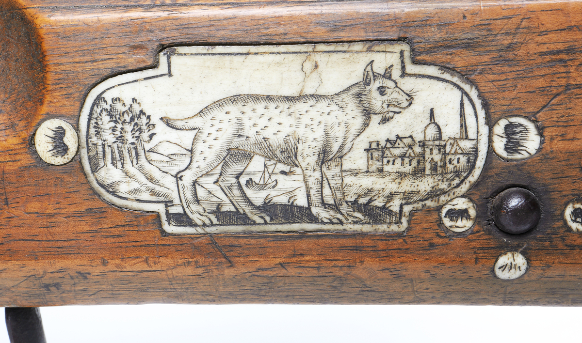 Armborst tillverkat i valnötsträ med båge av stål, försedd med inbygt lås med snälltryck. Stocken har inläggningar av elfenben i medaljonger, vari djur är ingraverade. På kindsidans plattor syns vildsvin, björn, löpande hund och vilande lejon, och på yttersidan löpande hundar, lo och springande hare och lejon. På kolvens översida finns två rankornerade plattor och tumgrepp med skraffering. Bakplåten i elfenben har en inristad krans. Skenan över pilrännan är fastskruvad vid stocken med två järnskruvar. På denna skena finns också sikte och korn av järn. Bågen i stål är i rektangulär genomskärning och hålls fast i kolven med en båglindning. Framför bågen finns en liten bygel i järn, och även varbygeln undertill är i järn. För att spänna bågen så krävs en hävstång eller vindspel för att göra detta. Armborstet har åtta pilar. (Inv. nr. L 3 - L 10), samt spännanordning.
Inskrivet i huvudkatalogen 1794.