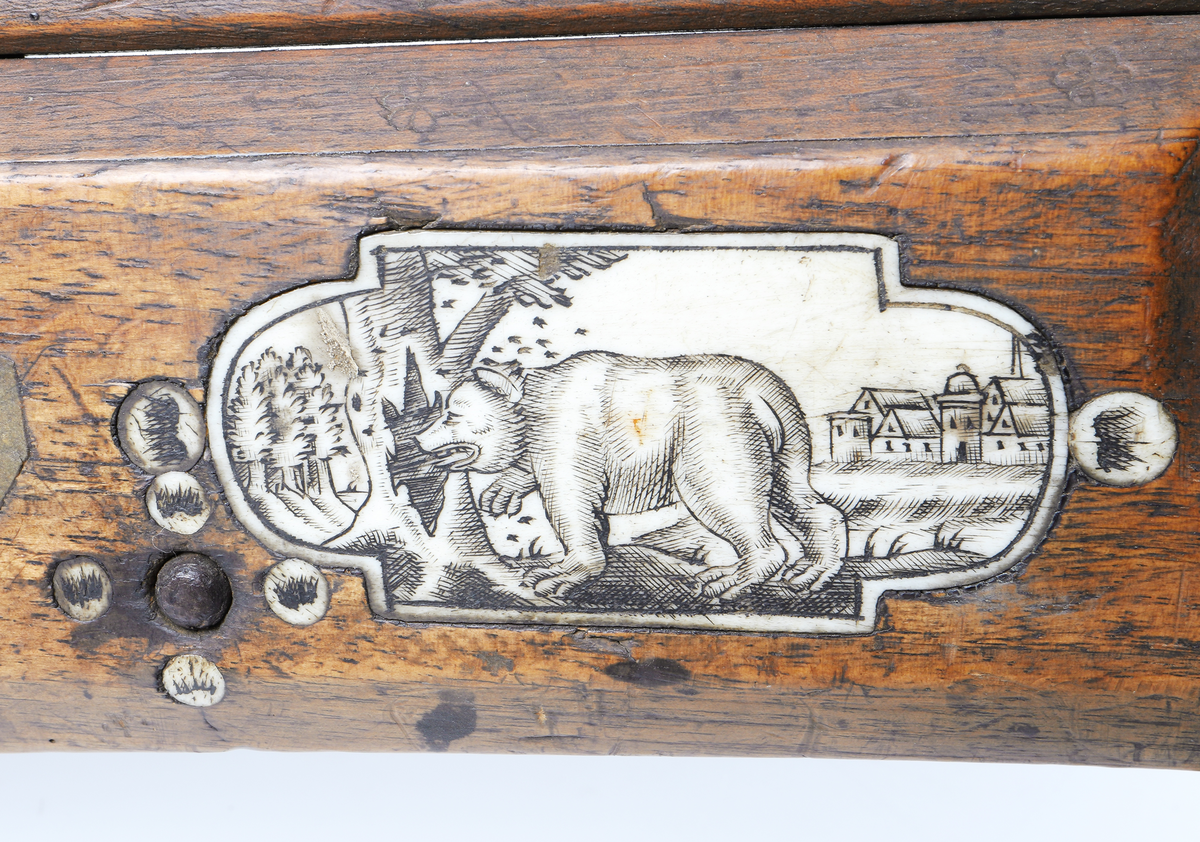 Armborst tillverkat i valnötsträ med båge av stål, försedd med inbygt lås med snälltryck. Stocken har inläggningar av elfenben i medaljonger, vari djur är ingraverade. På kindsidans plattor syns vildsvin, björn, löpande hund och vilande lejon, och på yttersidan löpande hundar, lo och springande hare och lejon. På kolvens översida finns två rankornerade plattor och tumgrepp med skraffering. Bakplåten i elfenben har en inristad krans. Skenan över pilrännan är fastskruvad vid stocken med två järnskruvar. På denna skena finns också sikte och korn av järn. Bågen i stål är i rektangulär genomskärning och hålls fast i kolven med en båglindning. Framför bågen finns en liten bygel i järn, och även varbygeln undertill är i järn. För att spänna bågen så krävs en hävstång eller vindspel för att göra detta. Armborstet har åtta pilar. (Inv. nr. L 3 - L 10), samt spännanordning.
Inskrivet i huvudkatalogen 1794.