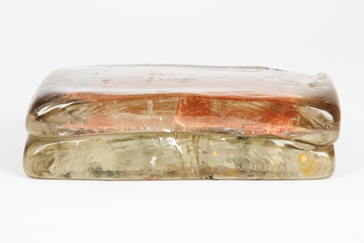 Glassform i klart glass med innlagt dekor. Består av to rektangulære flater som er smeltet sammen med et kobbernett og en gullfarget plate mellom.