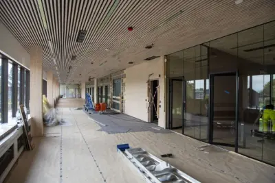 Tak med langsgående trespiler, glv dekket med gråpapir, vegger i glass og tre.