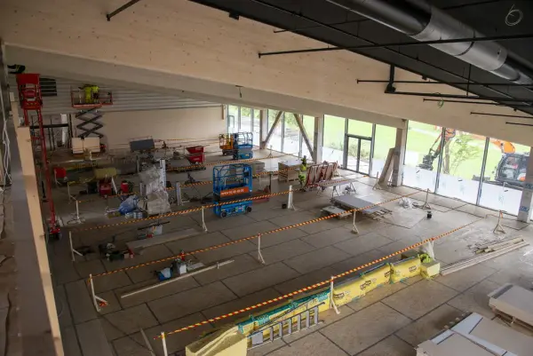 Fra kontorfløyen i 2. etasje ser man ned på utstillingsarealet, som er delt inn med sperrebånd og har flere lifter stående som hjelp i konstruksjonen.