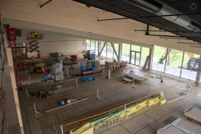 Fra kontorfløyen i 2. etasje ser man ned på utstillingsarealet, som er delt inn med sperrebånd og har flere lifter stående som hjelp i konstruksjonen.