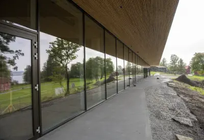 Glassfasaden på det regionale historiesenteret speiler flott husene og naturen rundt senteret, mye takket være et stort takutstikk som hinder sollys direkte på vinduene.